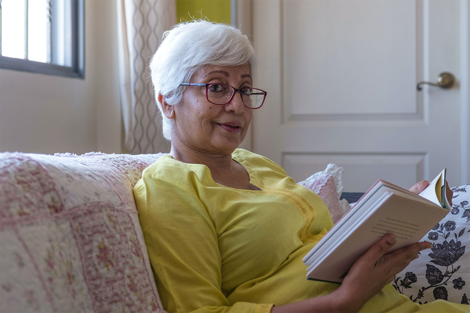 elderly woman in a yellow jumper reading a book