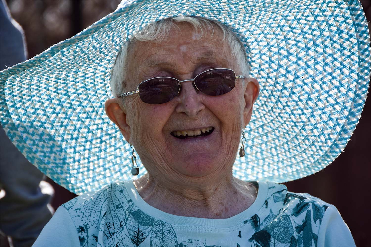older woman in sun hat and sunglasses smiling