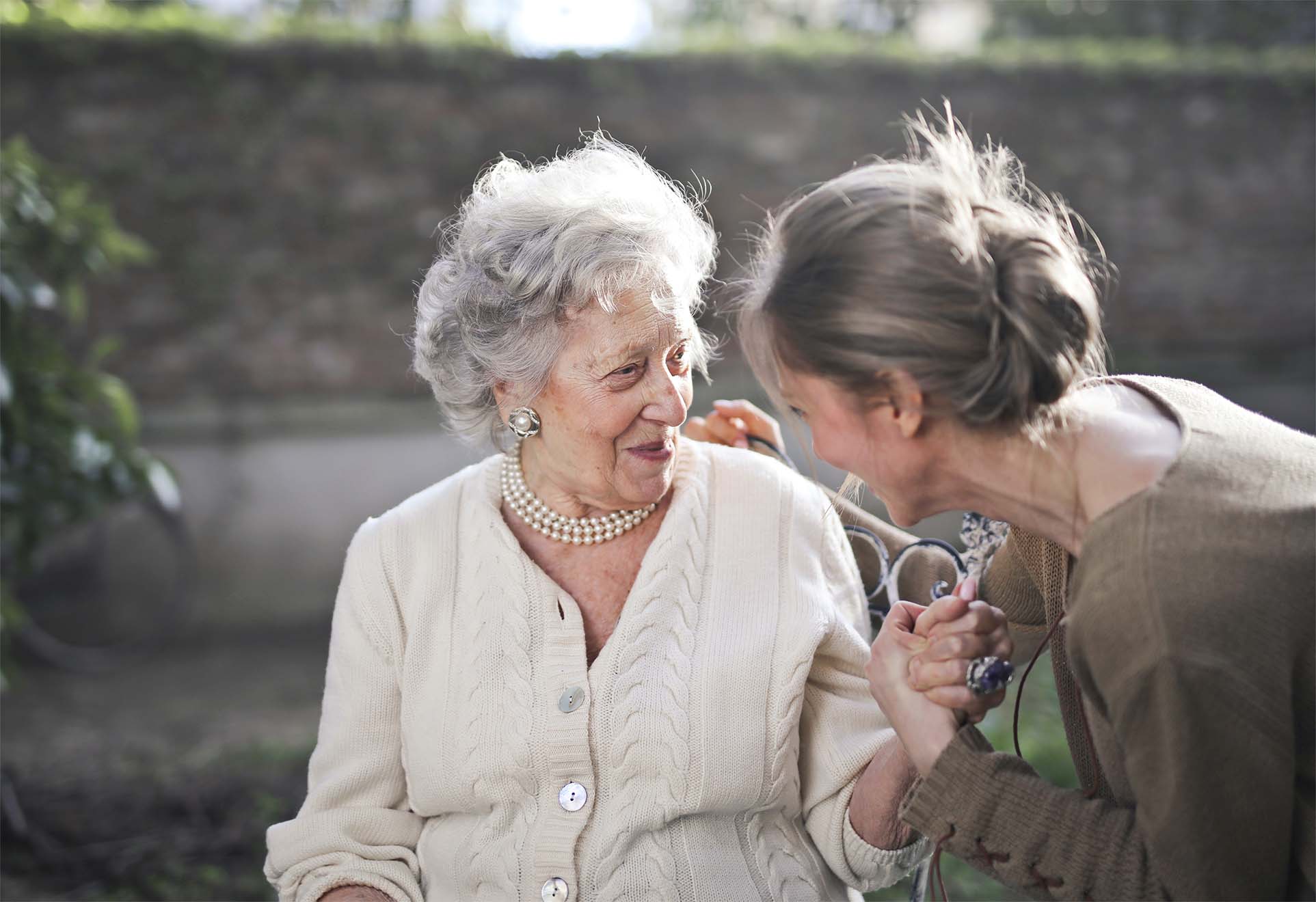 staff member smiling with an elderly resident in a garden
