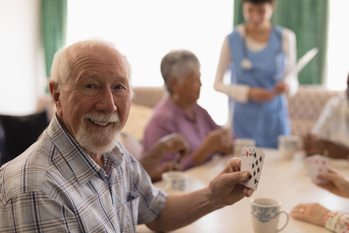 senior man playing cards in care home lounge