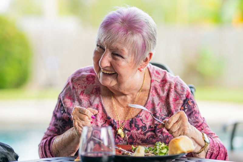 female resident wearing a pink top enjoying a meal